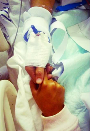 Georgie's hand being held by a visitor in the hospital