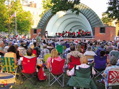 Concert-goers sitting in lawn chairs at Bandshell Park