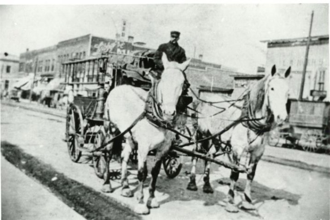 Circa 1915photo of a horse-driven hose cart going down the street.