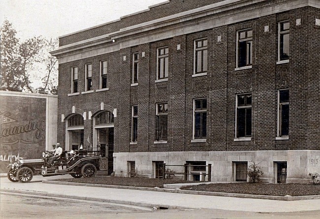 1921 City Hall with a small motorized fire engine pulling out through the overhead door. 