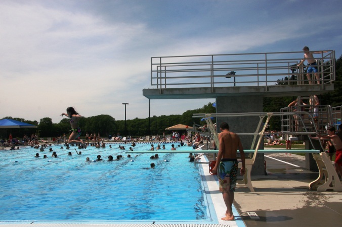 A child standing near the diving board at the Furman Aquatic Center