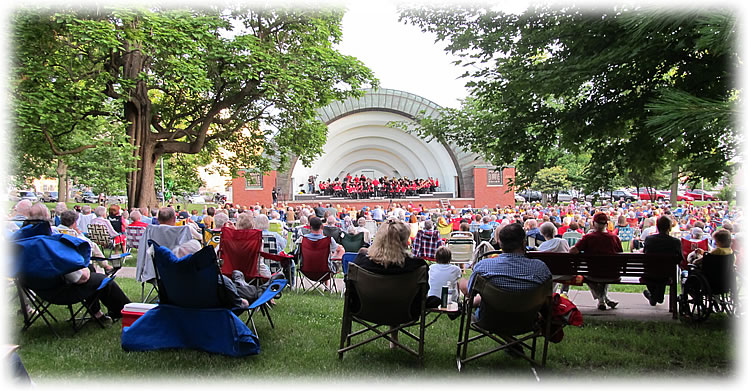 A large group of concert-goers in lawn chairs at Bandshell Park