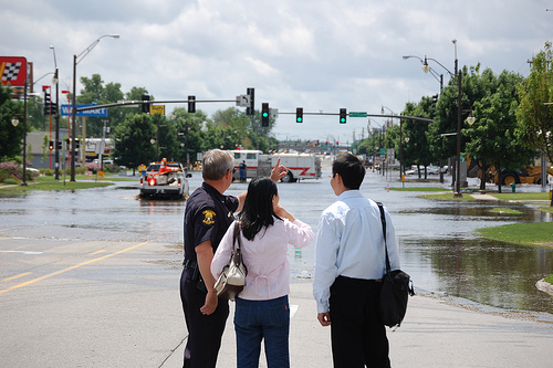 Ames Police Officer speaking with residents in front of flooded S. Duff in the Flood of 2008